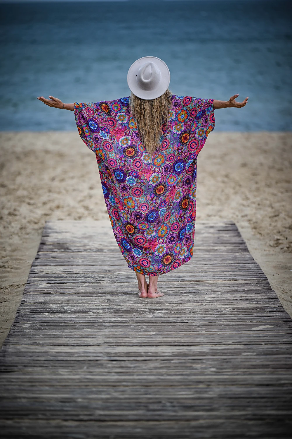 Patrycja Adaszewska stoi na pomoście tyłem do aparatu, z rozłożonymi ramionami nad wodą.