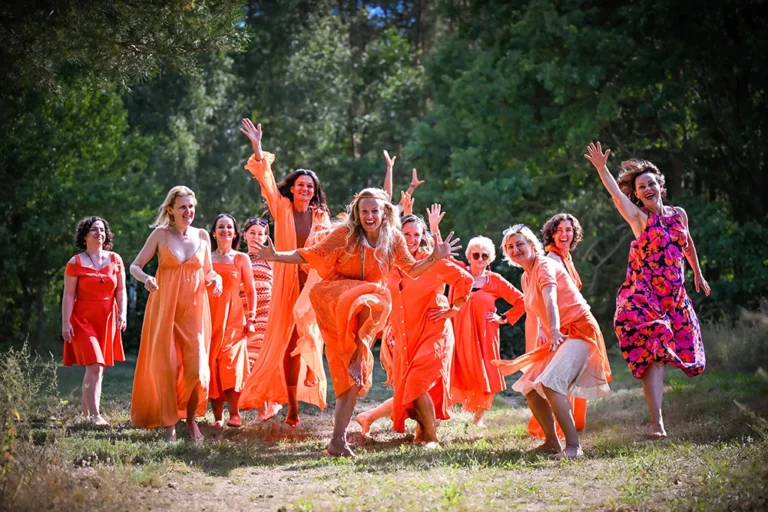 Uczestniczki obozu Kobieta w Pełni – radosne kobiety w pomarańczowych strojach podczas wspólnej zabawy.