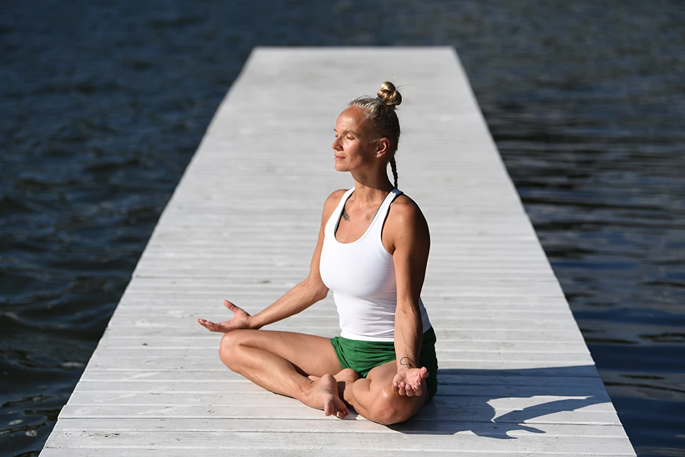 Patrycja Adaszewska medytuje na pomoście otoczonym wodą.